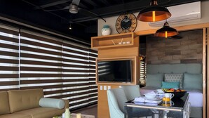A modern living room with a sofa, a coffee table, a TV, and a dining area with a table and chairs.