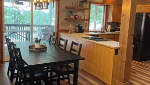 Una cocina moderna con armarios de madera, una isla central y un comedor con una mesa grande y sillas.