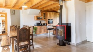 A modern kitchen with wooden cabinets, a central island, and a wood-burning stove. - LA MILONGA - AYN - Gîte (AYN)