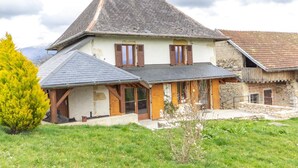 A two-story house with a sloped roof, wooden shutters, and a stone foundation. - LA MILONGA - AYN - Gîte (AYN)