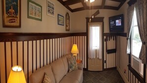 A room with a sofa, a lamp, a television, and a window with curtains.