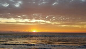 A sunset over the ocean with clouds in the sky.