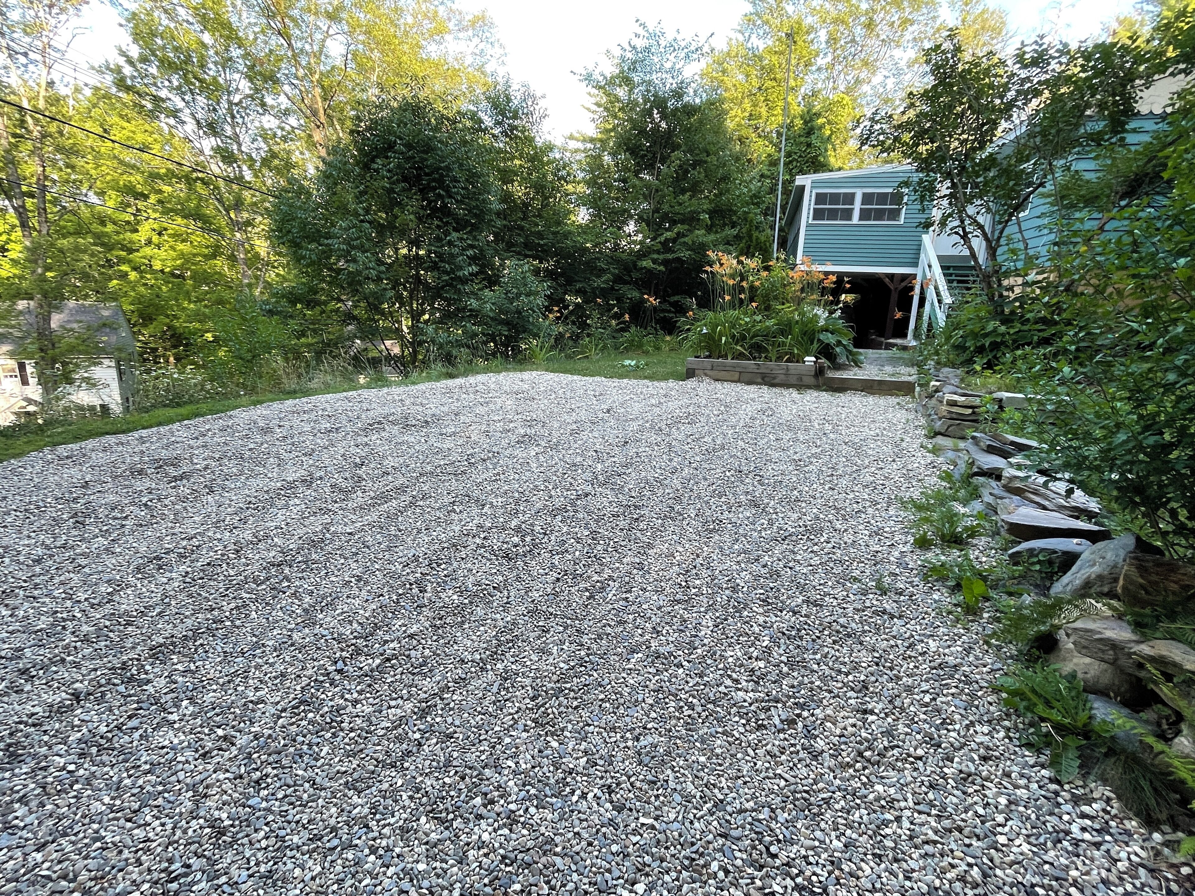 A gravel driveway leading to a house with a blue exterior.