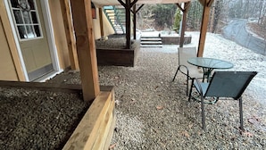 Un espacio de patio al aire libre con una pérgola de madera, una mesa con sillas y piso de grava.
