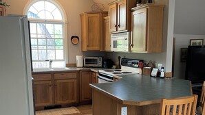 Una cocina con armarios de madera, microondas integrado y una isla grande con taburetes de bar.