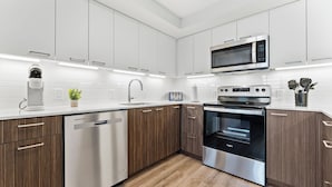 Una cocina moderna con armarios blancos, electrodomésticos de acero inoxidable y piso de madera.