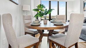 Un comedor moderno con una mesa redonda de madera, cuatro sillas tapizadas y una planta en maceta.