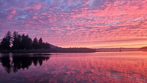 A calm lake reflecting a sunset sky with trees on the left. - The Queen 2 Bedroom Apartment D (Craig)