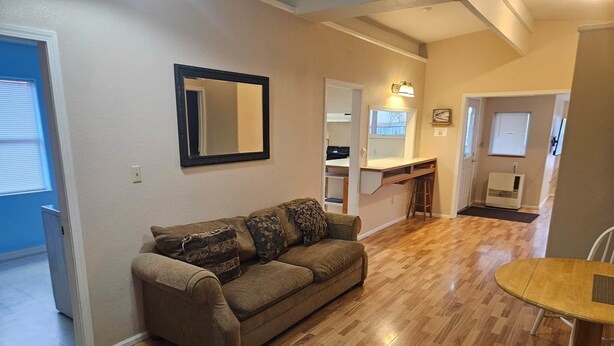 A living room with a sofa, a dining table, and a kitchen area in the background. - The Queen 2 Bedroom Apartment D (Craig)