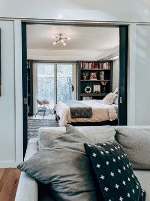 Ein Schlafzimmer mit Bett, einer Bücherwand und Blick ins Freie.