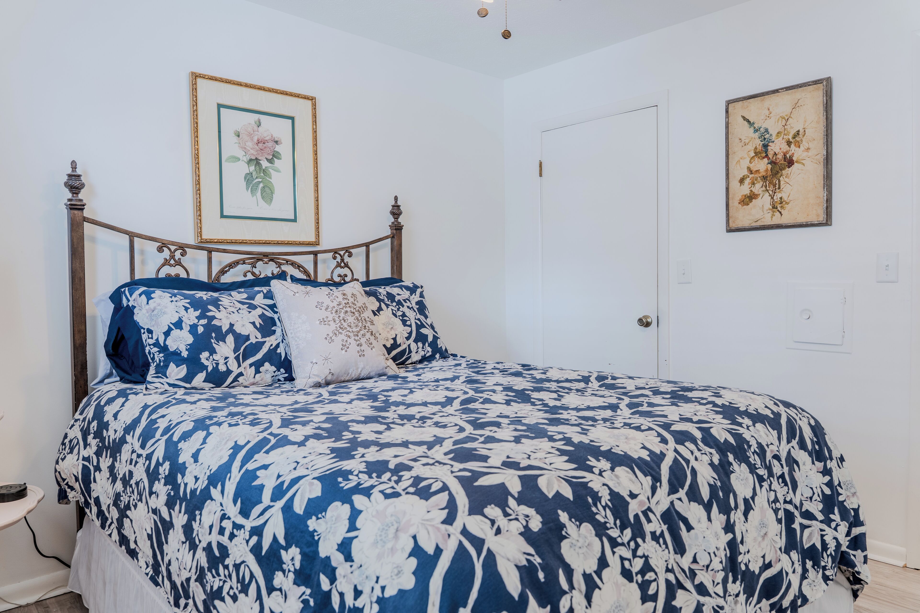 A bedroom with a bed, a nightstand, and a wall-mounted painting.
