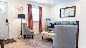 A living room with a sofa, armchairs, a lamp, a rug, and a window with curtains. - Charming Creekside Cottage [] Near Downtown, OSU & Airport (Gahanna)