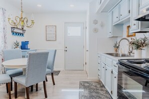 Una cocina moderna con armarios blancos, una estufa negra y un comedor con sillas azules.