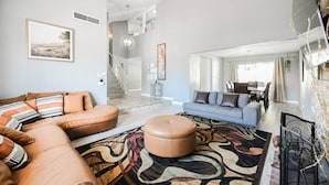 A spacious living room with a large sectional sofa, a blue sofa, and a patterned rug. - The Nuevo Luxe Villa (Henderson)