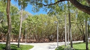 A pathway through a park with trees and metal benches. - Updated & Spacious 2-Bedroom, 2-Bath Home Just Steps from the beach (Miami Beach)