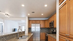 A modern kitchen with granite countertops, stainless steel appliances, wooden cabinets, and a tiled floor. - Updated & Spacious 2-Bedroom, 2-Bath Home Just Steps from the beach (Miami Beach)