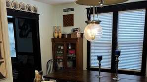 A kitchen with a marble countertop, wooden cabinets, a chandelier, and a view of the street.