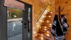 A wooden staircase with a handrail and a coat rack with various garments.