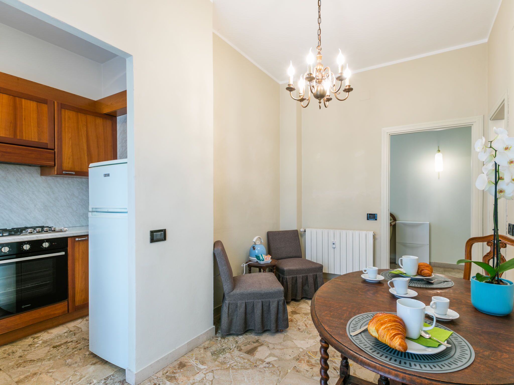 A compact kitchen with modern appliances, a dining area with a table set for breakfast, and a cozy seating arrangement.