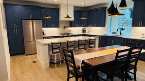 Une cuisine moderne avec des meubles de couleur bleu foncé, des appareils en acier inoxydable et un îlot central doté de tabourets de bar.