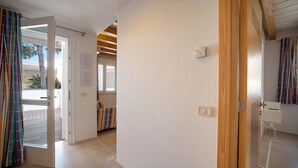 Un couloir avec une porte en bois, un mur blanc et une fenêtre.