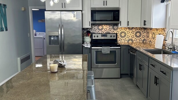 A modern kitchen with a granite countertop, stainless steel appliances, and pendant lighting. - Charming 4-bedroom house just a Short walk to Scarborough Beach (Narragansett)