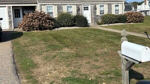 A two-story house with a front porch, a mailbox, and a well-maintained lawn. - Charming 4-bedroom house just a Short walk to Scarborough Beach (Narragansett)