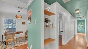 A room with a dining area, a wooden floor, and a green accent wall.