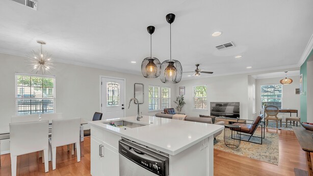 A modern kitchen with white cabinetry, a central island with a dishwasher, and pendant lighting.
