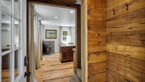 A wooden interior with a fireplace, a kitchen area, and a dining table. - Cozy Forest Cabin, Hot Tub, King beds, AC, Fast Wi-fi, Waterfront, Pet Friendly (Rhododendron)