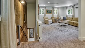 A spacious living room with a beige sofa, a coffee table, and a patterned rug. - Cozy Forest Cabin, Hot Tub, King beds, AC, Fast Wi-fi, Waterfront, Pet Friendly (Rhododendron)