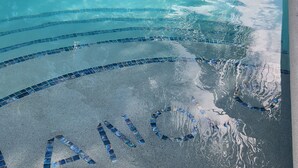Ein Schwimmbecken mit einer gefliesten Umrandung und einem kreisförmigen Muster auf dem Boden.