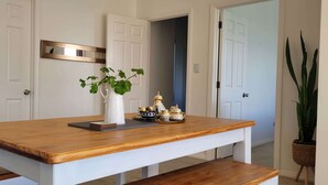 A wooden dining table with a white bench, a vase with green leaves, and a tray with decorative items. - Elevated Family Sized Guest-house with Beautiful Views (Auckland)