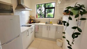 A compact kitchen with a refrigerator, stove, and sink. - Elevated Family Sized Guest-house with Beautiful Views (Auckland)