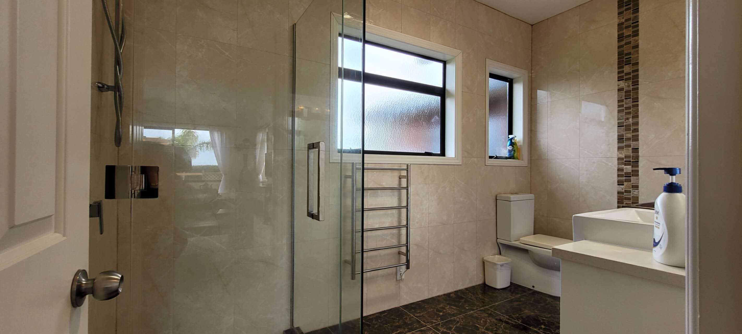 Une salle de bain moderne avec une douche à parois de verre, des toilettes et un lavabo.