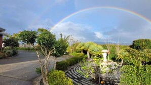 A garden with a fountain, a rainbow, and a house in the background. - Elevated Family Sized Guest-house with Beautiful Views (Auckland)