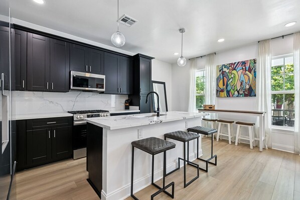 A modern kitchen with dark cabinets, a white island, and bar stools.