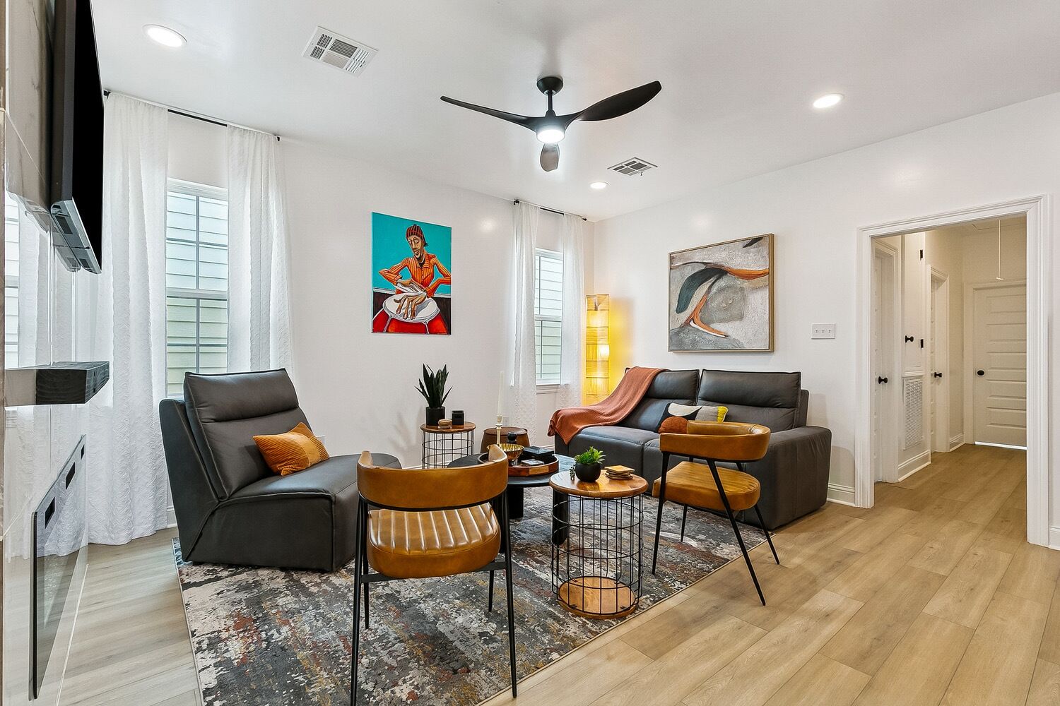 A modern living room with a sofa, chairs, a coffee table, and artwork on the walls.
