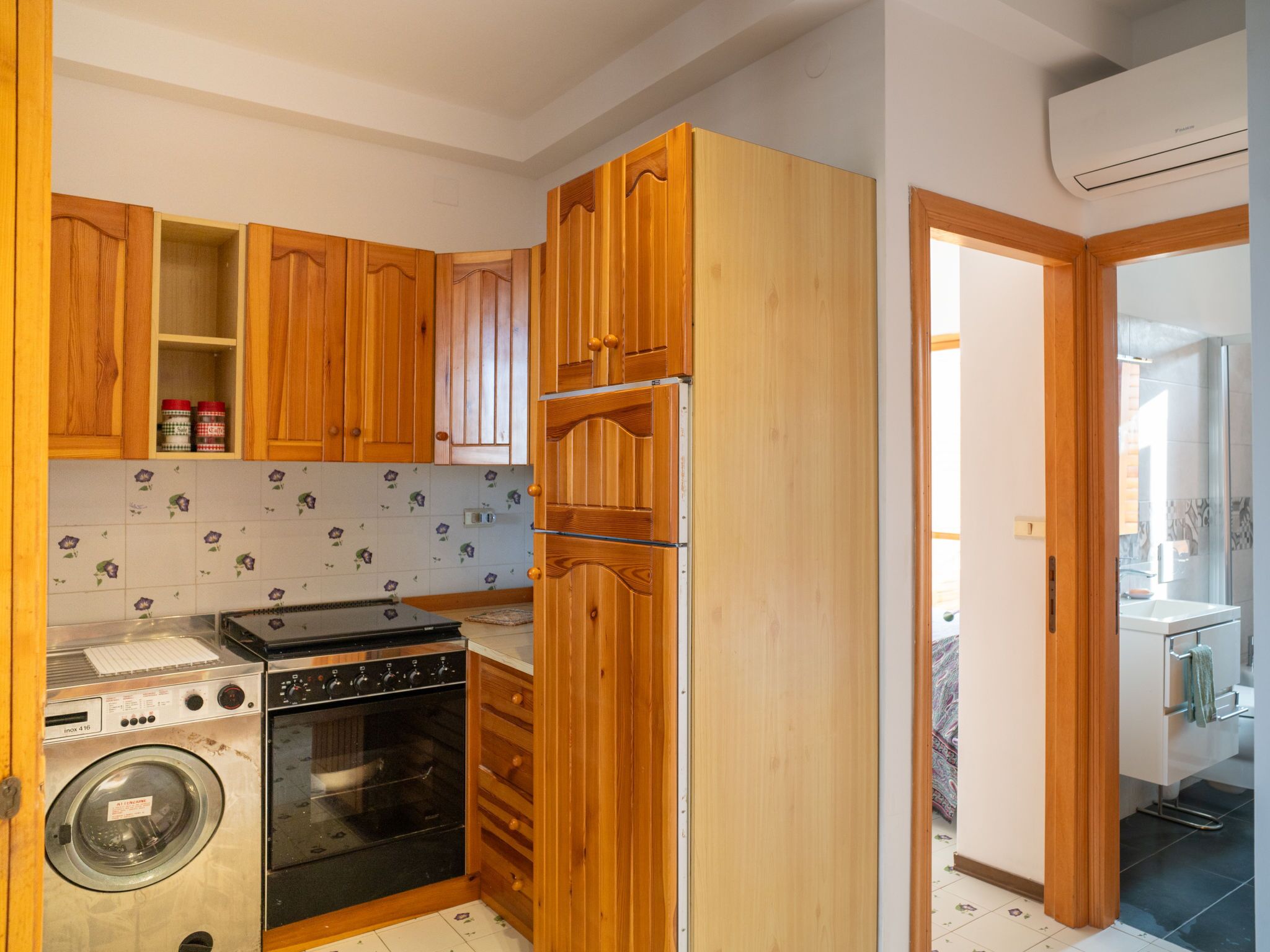 A compact kitchen with wooden cabinets, a washing machine, and an oven.