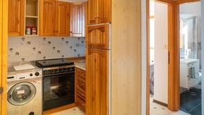Une cuisine de taille réduite, dotée de meubles en bois, d’un lave-linge et d’un four.