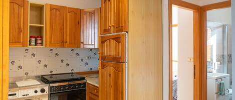 A compact kitchen with wooden cabinets, a washing machine, and an oven.
