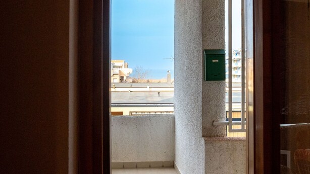 Une vue depuis un balcon, avec un ciel dégagé et des bâtiments en arrière-plan.