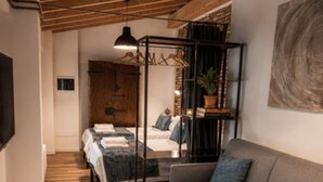 A modern bedroom with a bed, a sofa, a hanging light fixture, and a wall-mounted television. - Borgovivo Loft A Modern Loft Bergamo City Center (Bergamo)