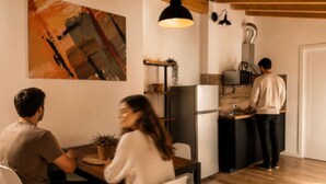 A modern kitchen with a dining area, wooden flooring, and a hanging pendant light. - Borgovivo Loft A Modern Loft Bergamo City Center (Bergamo)
