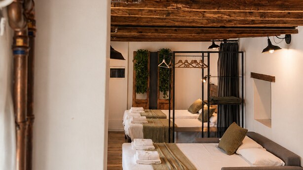 A hotel room with wooden beams, a bed, a desk, and a hanging plant. - Borgovivo Loft B Modern Loft Bergamo City Center (Bergamo)