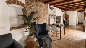 A modern living room with exposed wooden beams, a brick wall, and a dining area with a table and chairs. - Borgovivo Loft B Modern Loft Bergamo City Center (Bergamo)