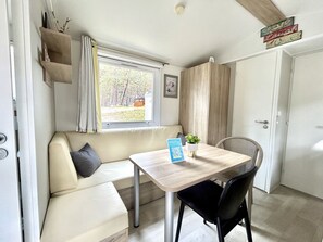 A compact room with a sofa, a table, a chair, a window, and a door.