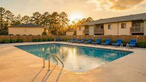 A swimming pool with sunbathing chairs and a wooden fence. - Recreation Central ILM (Wilmington)