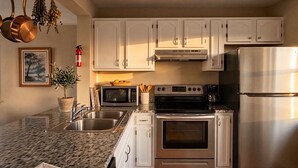 A modern kitchen with stainless steel appliances, white cabinetry, a granite countertop, and a fire extinguisher. - Recreation Central ILM (Wilmington)
