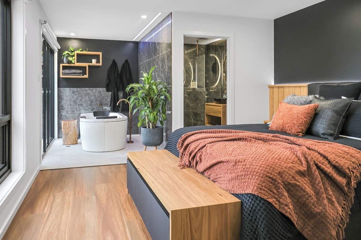 A modern bedroom with a bed, bedside table, and a large window.